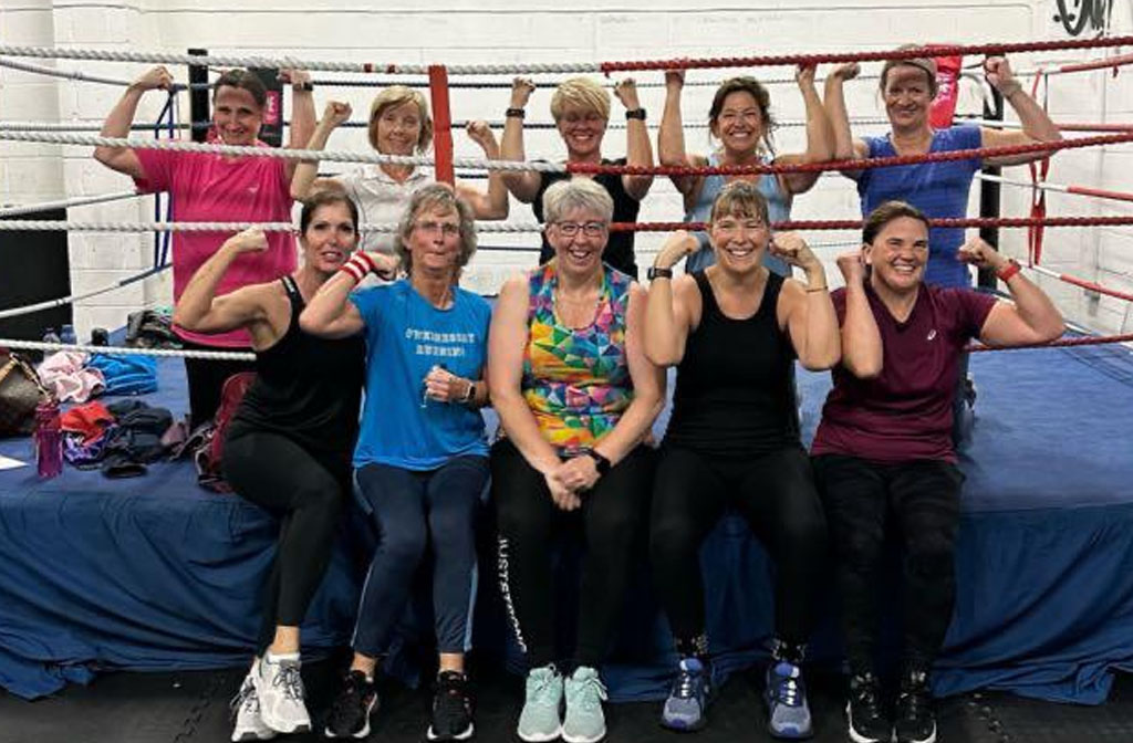 A group of women in fitness wear pictured posing in a boxing ring
