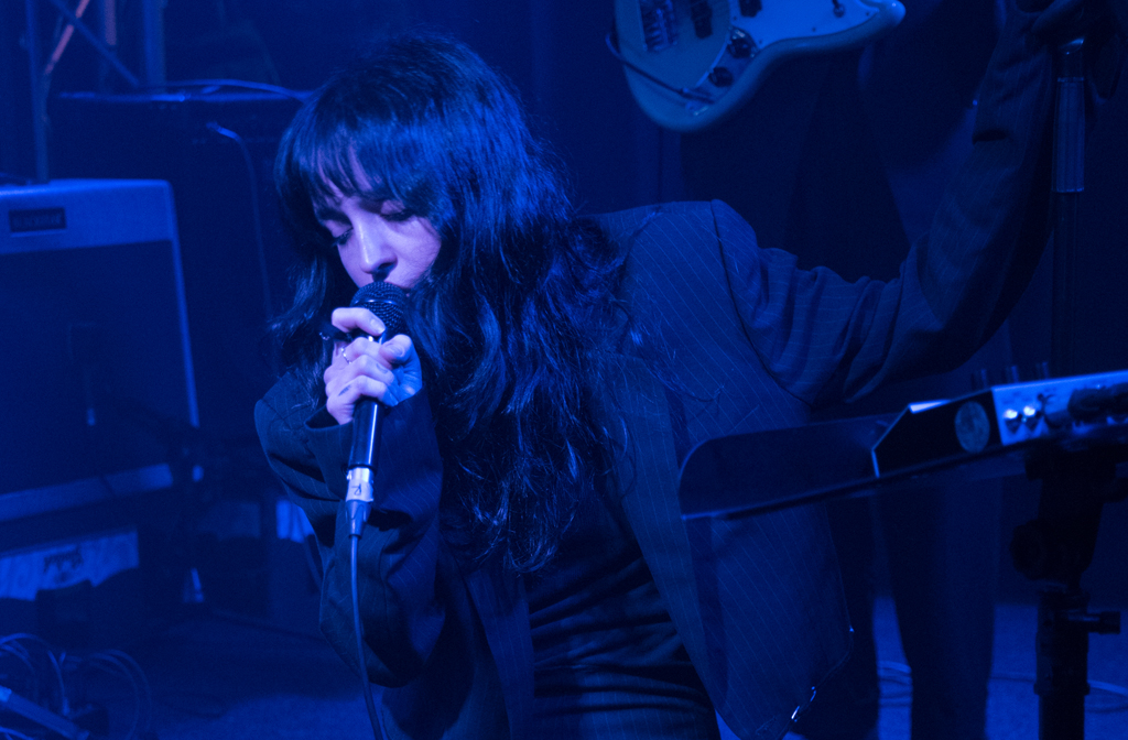 The lead singer of Velvetine is crouching on the stage at Bedford Esquires