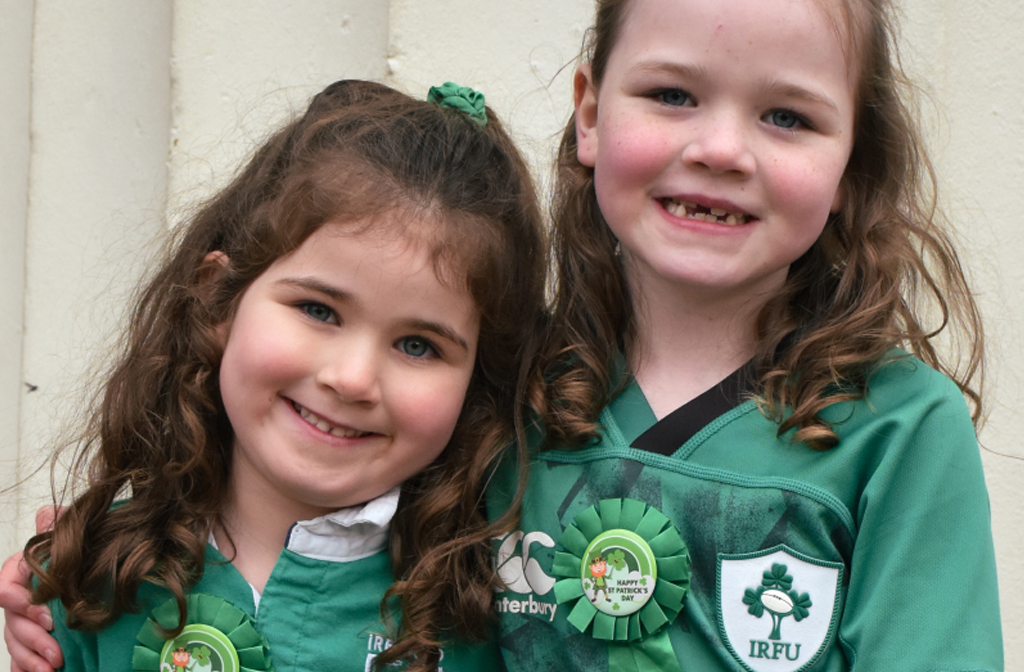 Two young girls dressed in Irish rugby tops celebrate St Patrick's Day